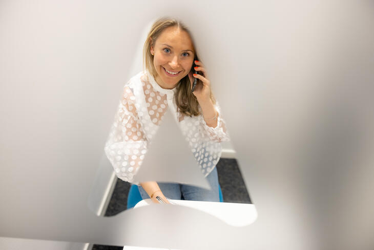 Kvinne på telefon ser opp gjennom frosta glass